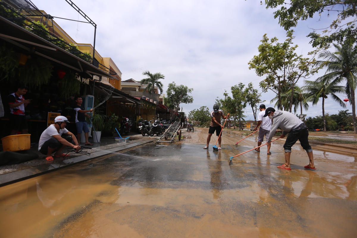 Người dân dọn dẹp lớp bùn non trên đường Bạch Đằng.