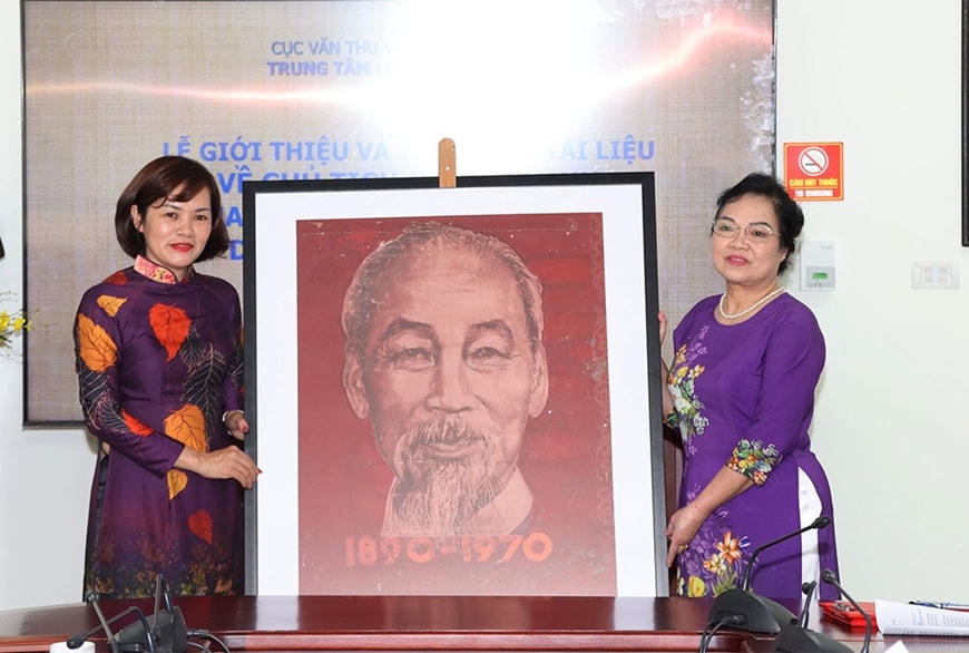 Bà Trần Việt Hoa - Giám đốc Trung tâm Lưu trữ quốc gia III (trái) tiếp nhận bức tranh vẽ bằng bột màu chân dung Chủ tịch Hồ Chí Minh do gia đình họa sĩ Bùi Trang Chước trao tặng.