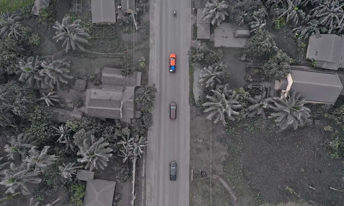 Các phương tiện chạy qua những ngôi nhà và thảm thực vật phủ đầy tro bụi ở thị trấn Juban sau khi núi lửa Bulusan phun trào. Ảnh: Getty Images.