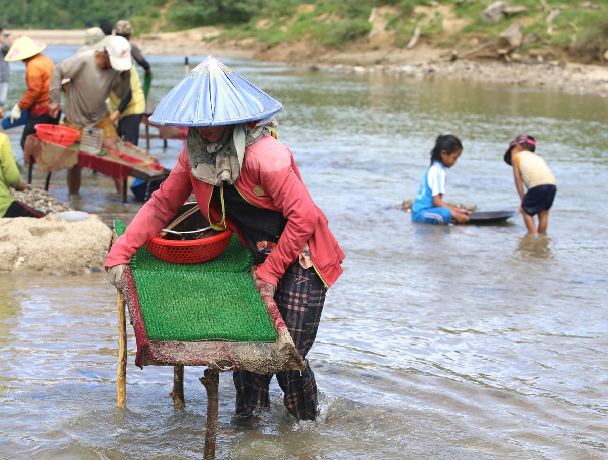 Cảnh người bắt máng đãi vàng dọc bờ hồ thủy điện.