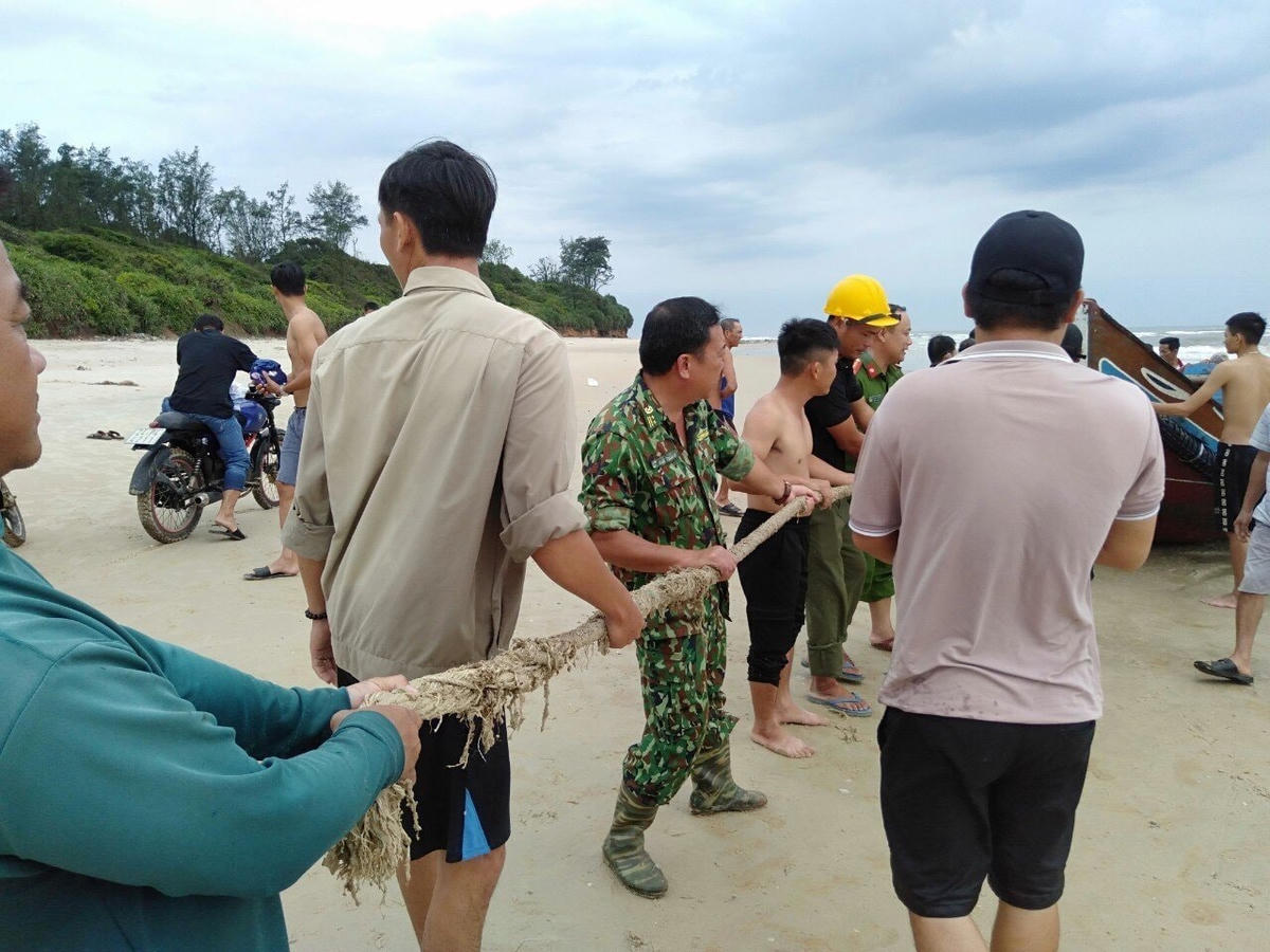 Lực lượng chức năng và người dân tiến hành trục vớt thuyền gặp nạn.