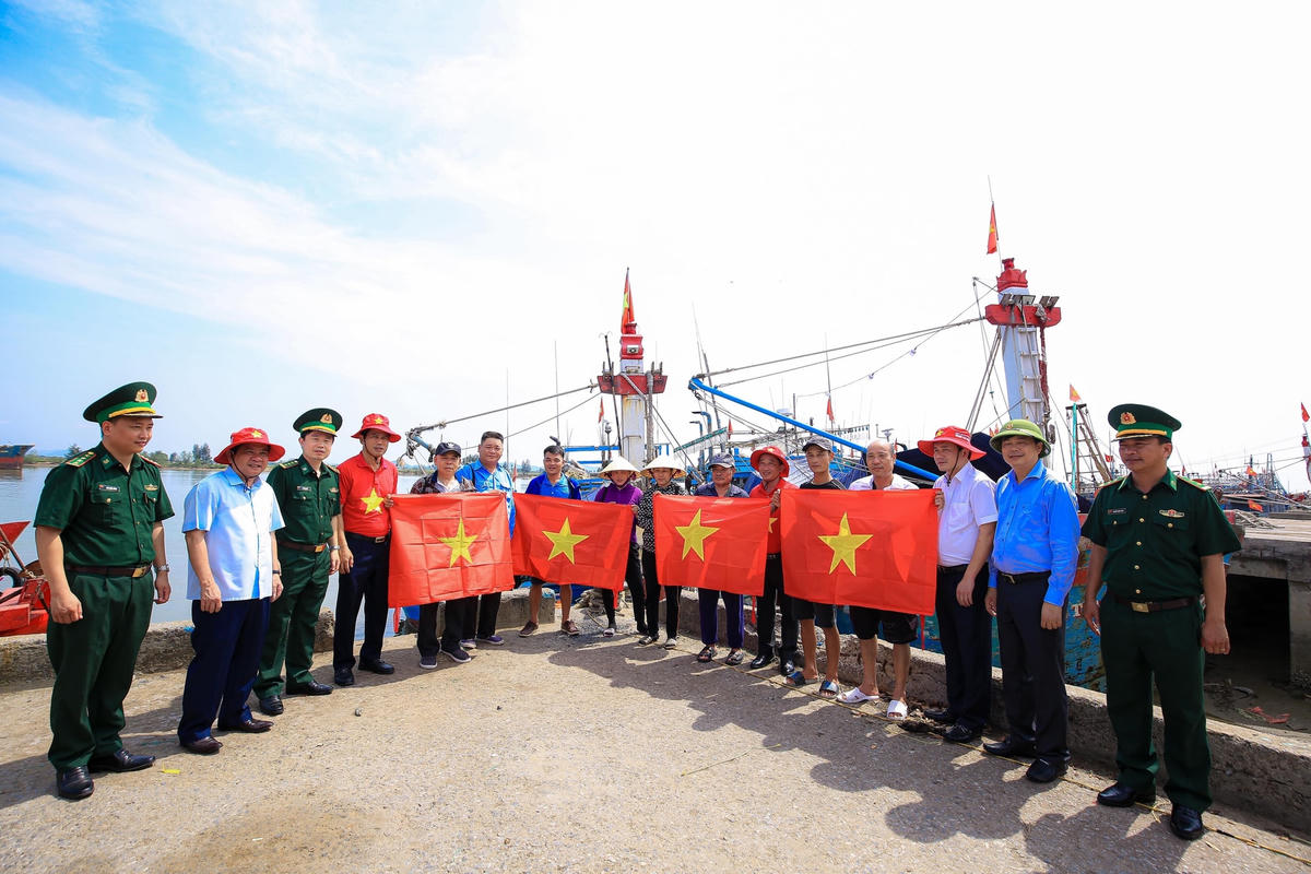 Đại diện Báo Người Lao động trao cờ cho các ngư dân hoạt động đánh bắt thủy hải sản ở ngoài khơi.