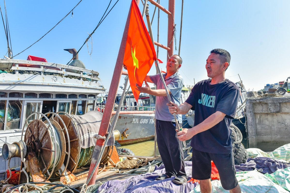 Người dân treo ngay cờ Tổ quốc lên nóc con tàu sau khi nhận cờ.