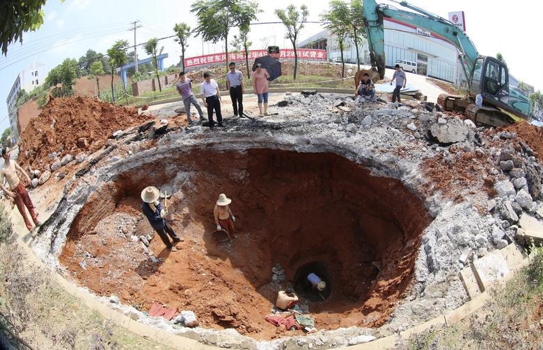 Một đội cứu hộ làm việc dưới khu vực bị sụt lún do "hố tử thần" gây ra trên một con đường ở Loudi, tỉnh Hồ Nam, Trung Quốc vào ngày 18/6/2013. Ảnh: Reuters.