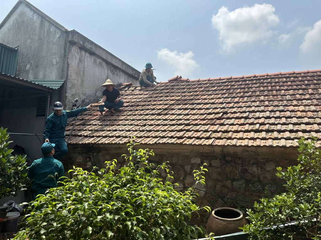 Lực lượng dân quân tự vệ phường Phong Hải, TX Quảng Yên hỗ trợ người dân lợp lại mái. Ảnh: Cao Quỳnh.