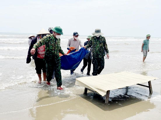 Lực lượng chức năng đưa thi thể nạn nhân vào bờ.