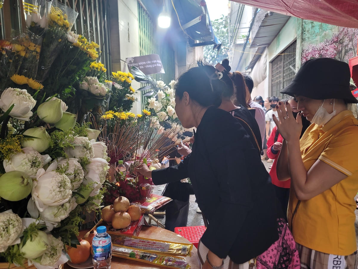 Người dân đội mưa đến chung cư mini bị cháy đặt hoa tưởng niệm các nạn nhân 