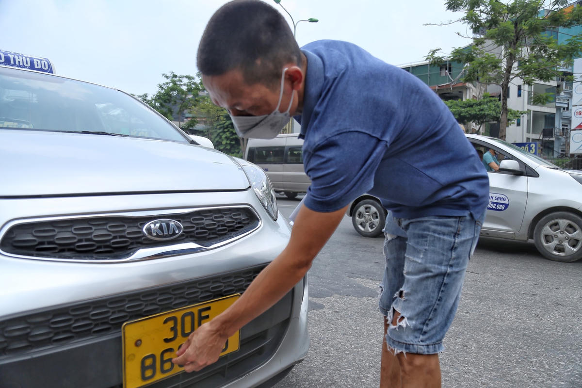 Tài xế bóc băng dính dán vào biển số sau khi bị xử phạt.