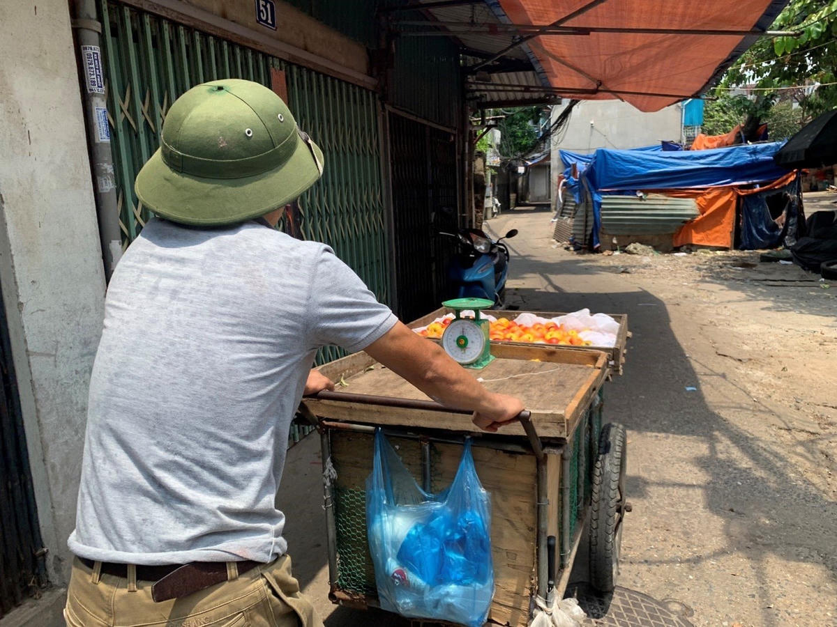 Anh Dũng - một người bán hàng rong quay về xóm trọ sau một ngày làm việc vất vả. Ảnh: Hoàng Minh.