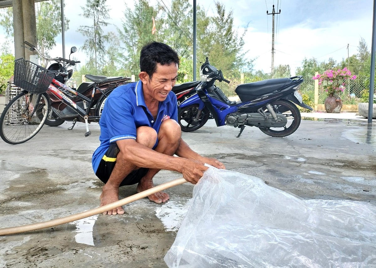 Ông Đoàn Tới đang bơm nước vào túi bóng chằng chống nhà cửa.