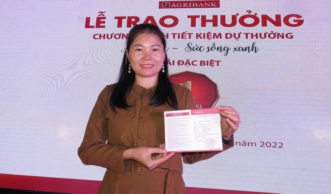 Khách hàng Trương Thị Hương Hoa cầm trên tay cuốn sổ tiết kiệm 1 tỷ đồng từ tiền trúng thưởng của chương trình.