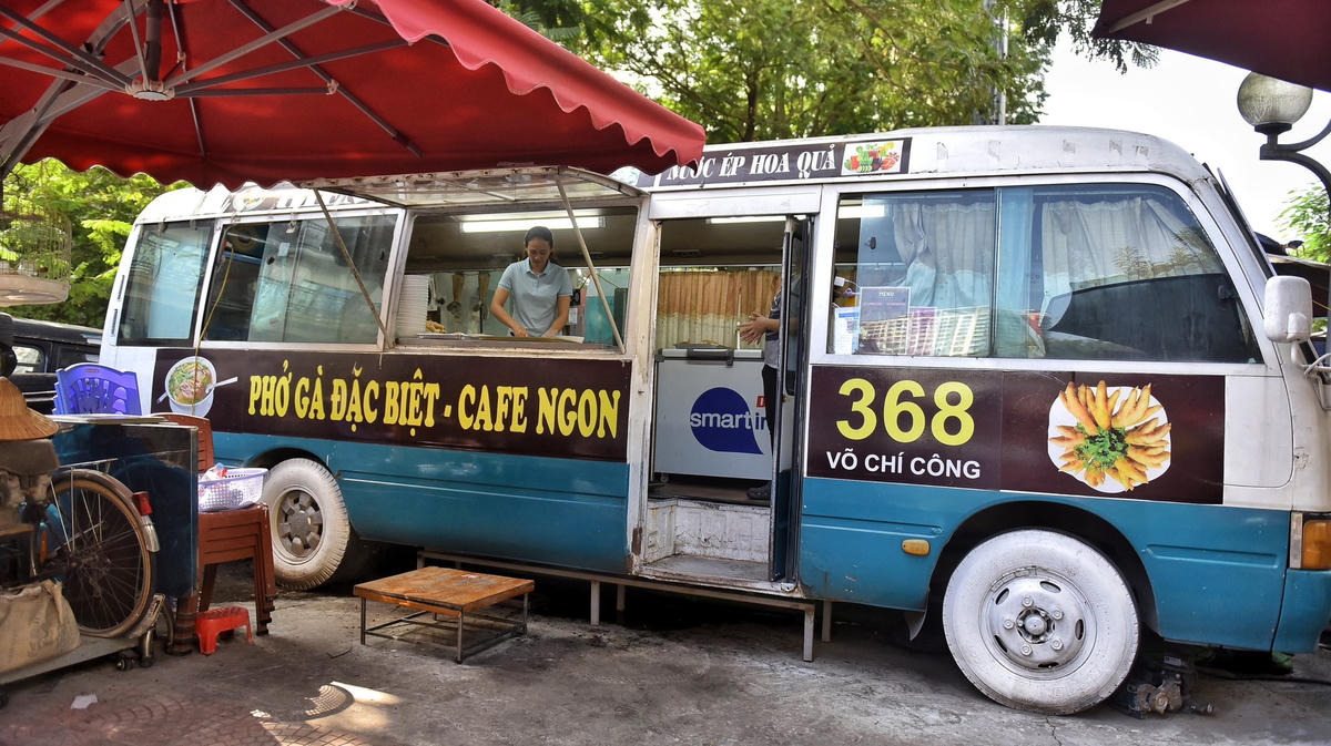 Thay vì bán phở trong những căn bếp hay hàng quán rộng rãi, quán phở gà nằm trên đường Võ Chí Công (Tây Hồ, Hà Nội) của chị Tạ Thị Thu Hiền lại sử dụng một chiếc xe ô tô 29 chỗ làm bếp phục vụ khách hàng.