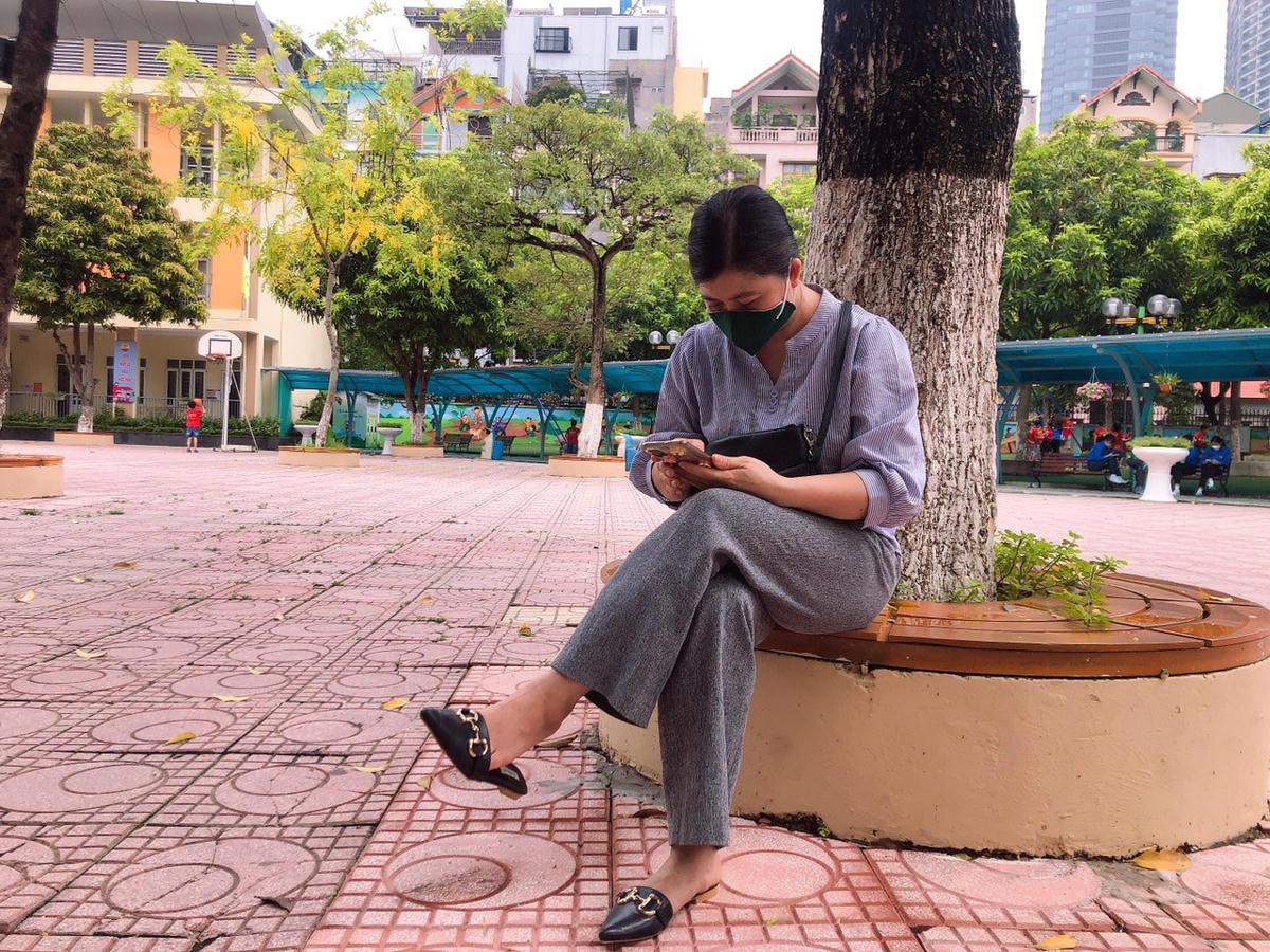 Chị Thủy (42 tuổi, phường Mỹ Đình 2) chọn bóng cây ngoài sân trường để ngồi chờ đợi.