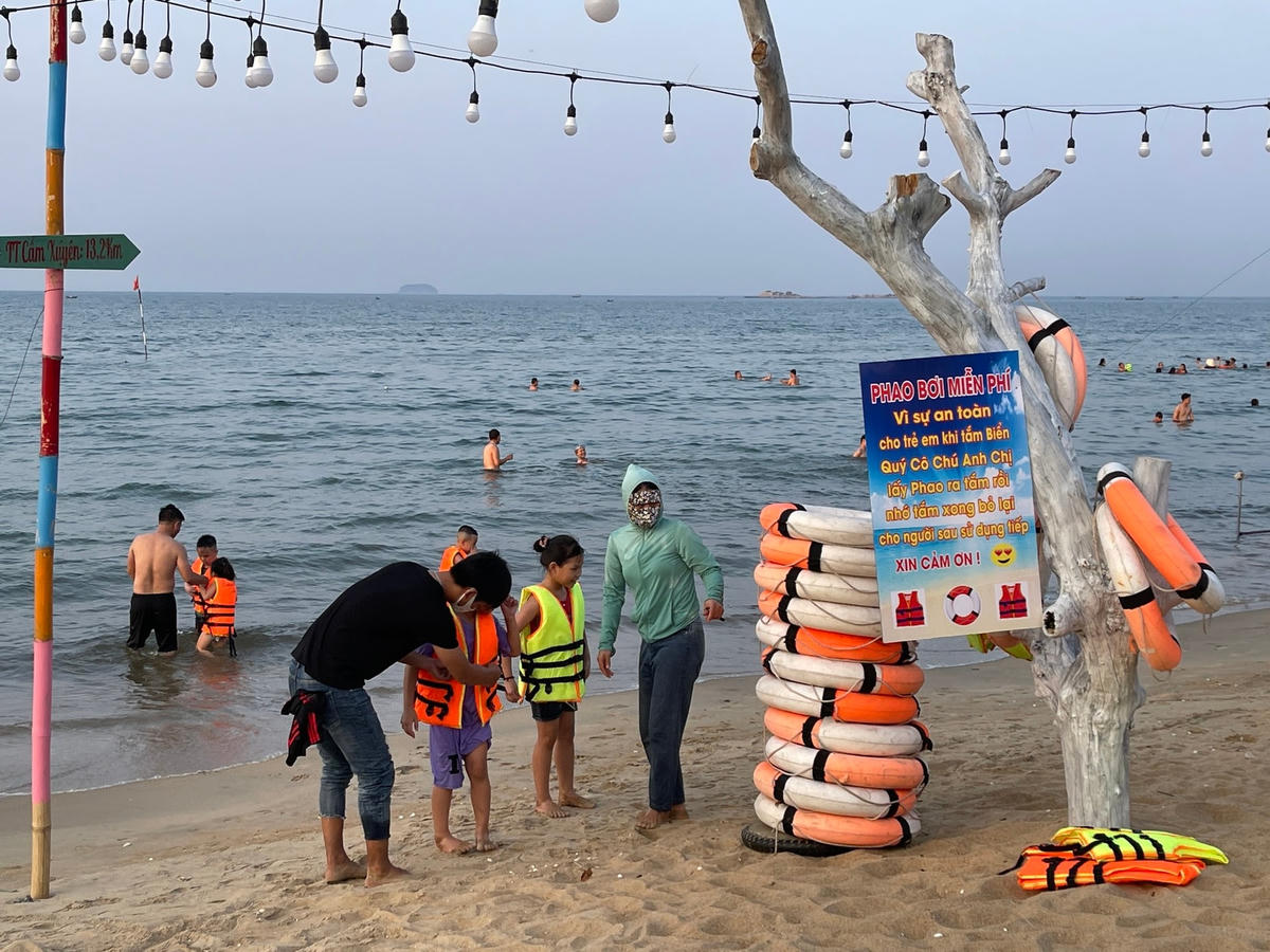 Hình ảnh những em nhỏ vui vẻ mặc áo phao miễn phí để tắm biển an toàn.