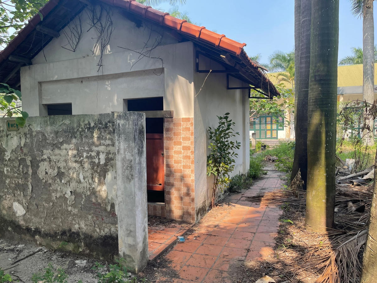 Khu vực nhà vệ sinh xuống cấp, cây cối, cỏ dại mọc um tùm xung quanh...