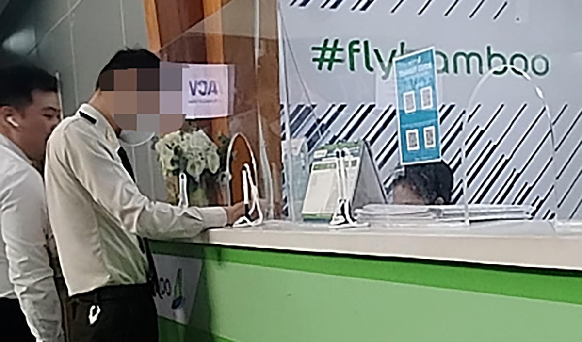 Một người mặc trang phục an ninh Cảng hàng không quốc tế Đà Nẵng trao cùng với người mặc trang phục hãng hàng không Bamboo Airways ký giấy để đưa hành khách không giấy tờ qua cửa an ninh sau khi người khách này chuyển gần 1,5 triệu đồng cho đại lý. Ảnh: cắt từ clip.