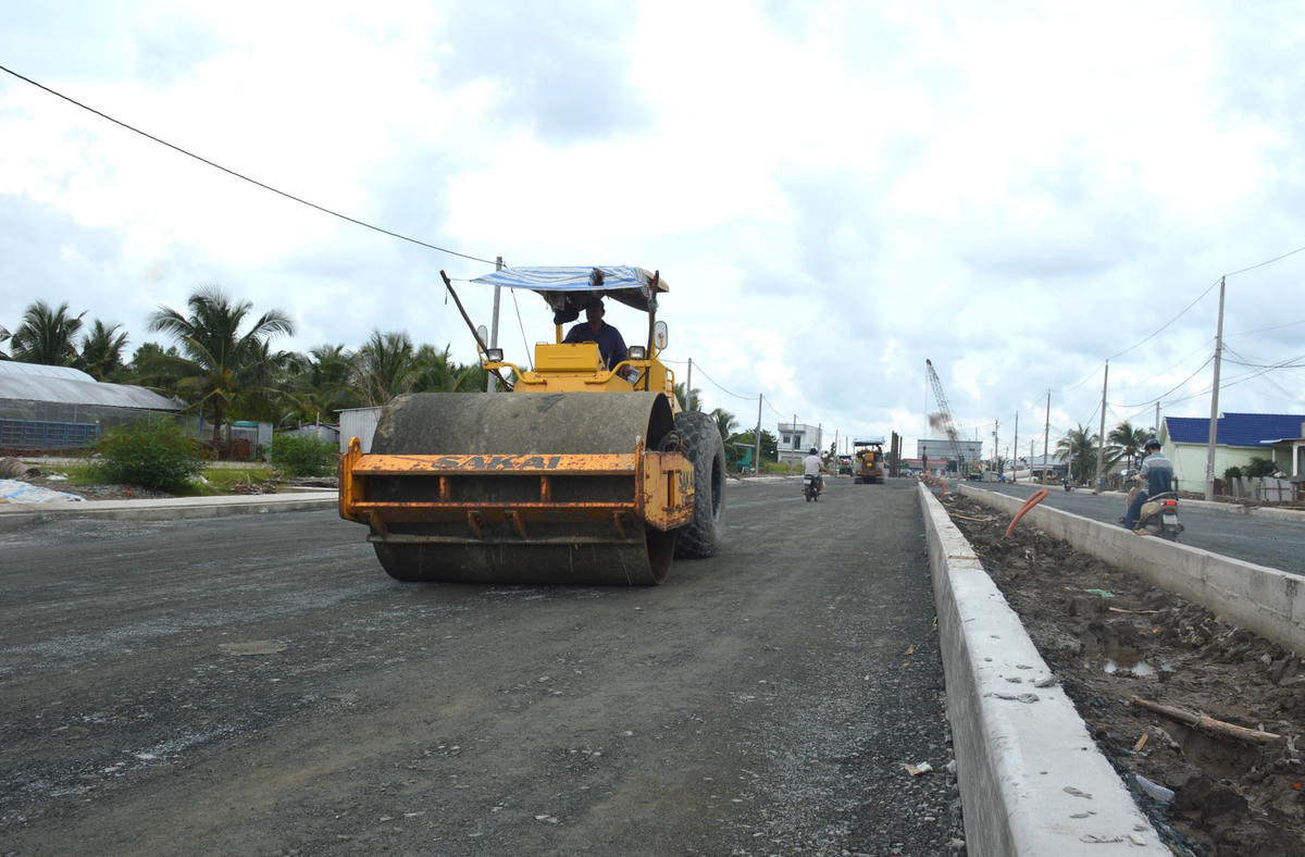 Xe lu mặt đường cấp phối đá dăm cho đường dẫn phía bờ Nam thị trấn Sông Đốc.