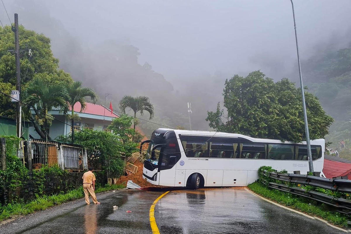 Một xe chở khách du lịch bị đất đá sạt lở chặn lối đi.