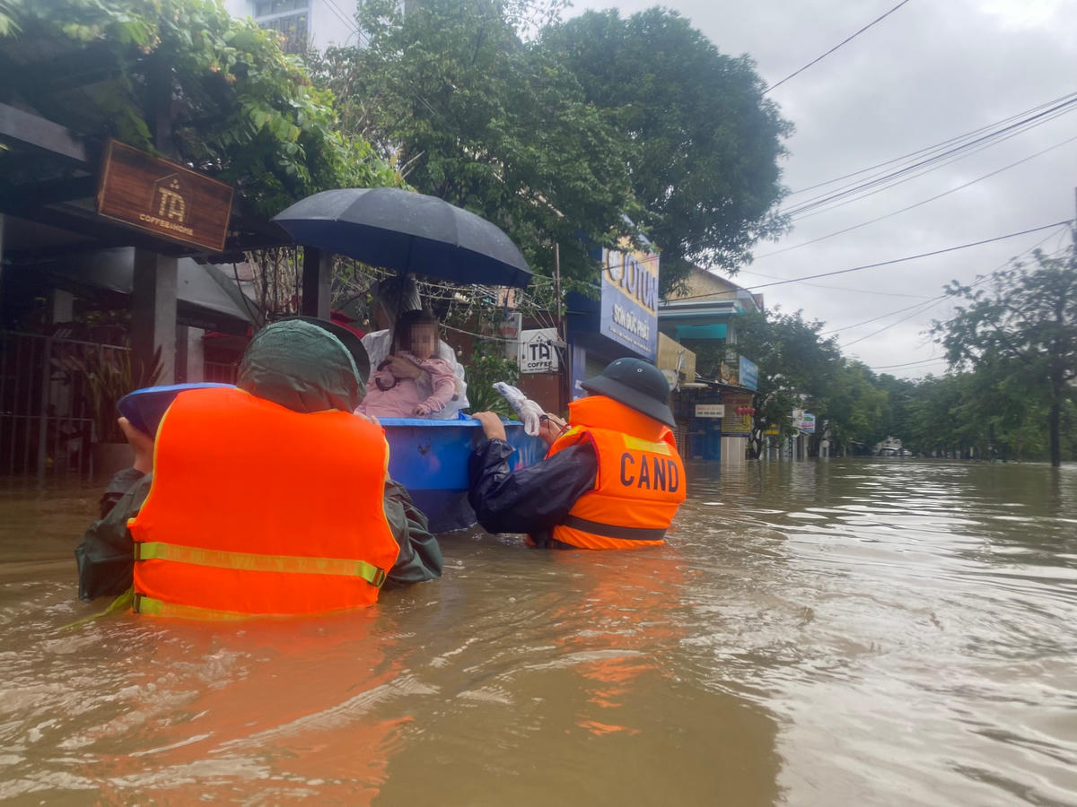 Công an hỗ trợ, đưa sản phụ cùng con nhỏ ở vùng lũ đến nơi an toàn. Ảnh: C.Q.