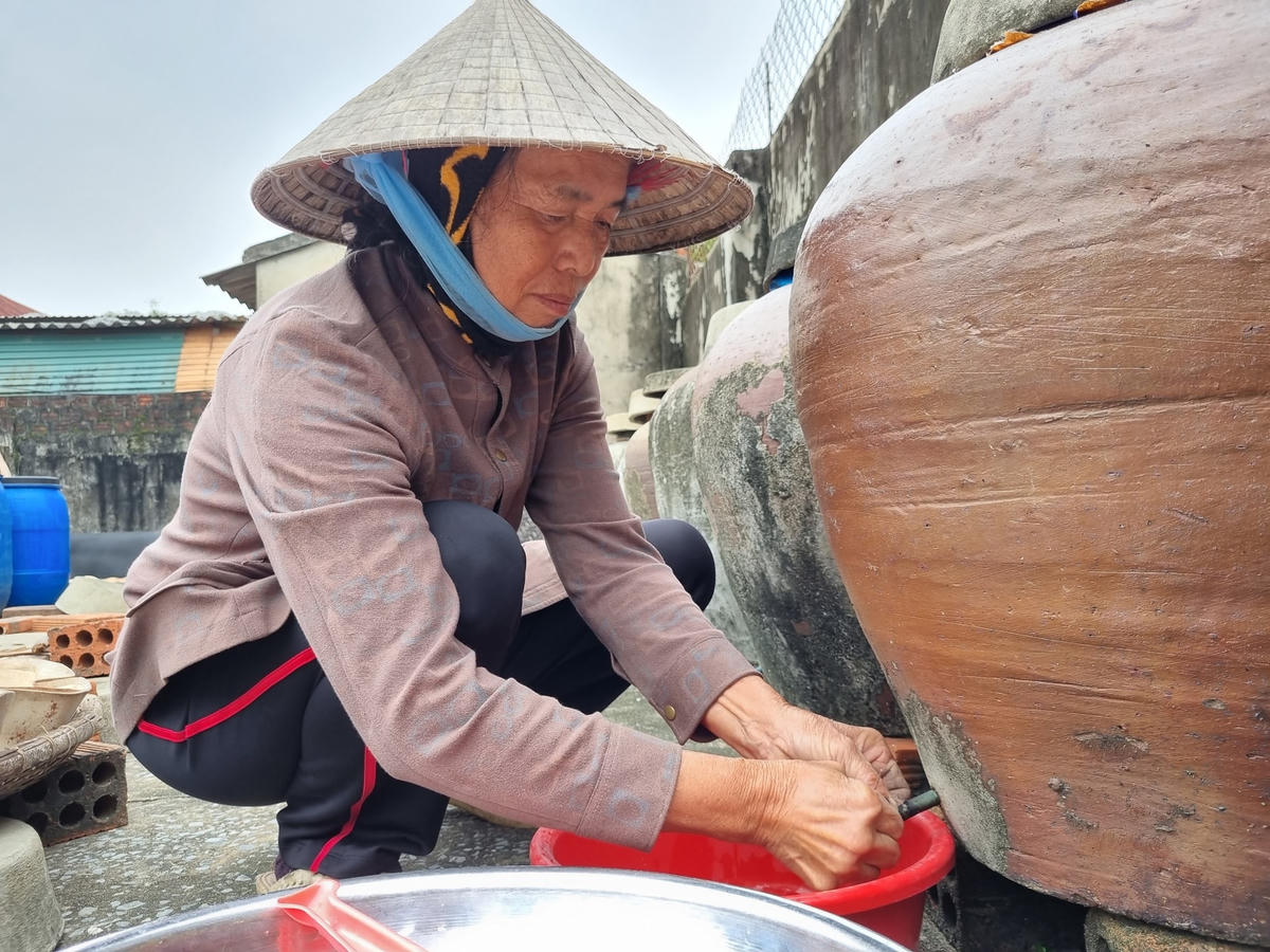 Bà Vinh cẩn trọng kiểm tra độ mặn của nước mắm ở từng chum.
