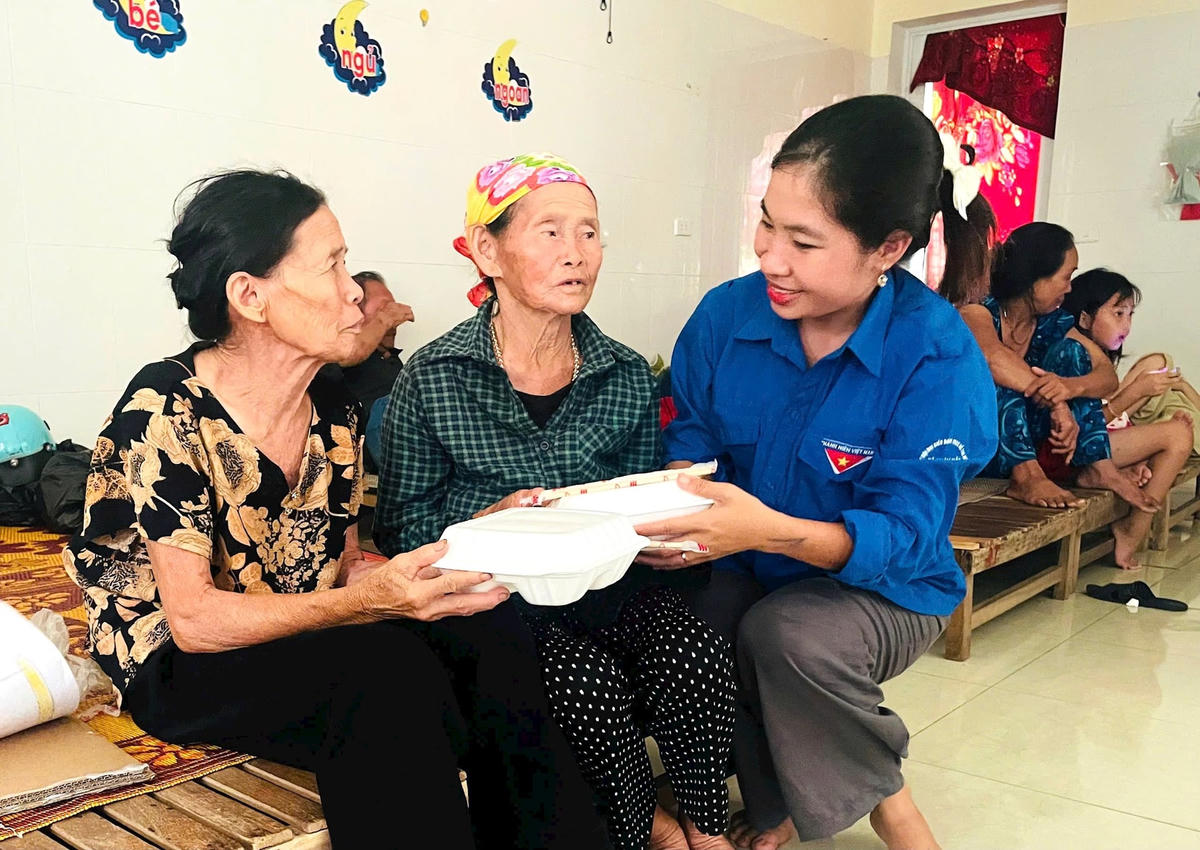 Bà Trần Thị Ngân (mặc áo hoa) xúc động nhận hộp cơm từ đoàn viên chi đoàn xã Đan Hải (Hà Tĩnh). Ảnh HN.