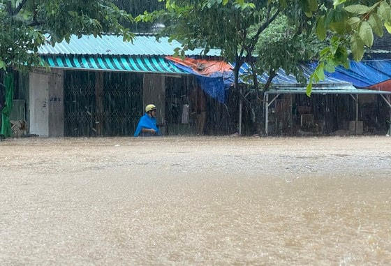 Một người dân lội qua điểm ngập sâu hơn 1m để cứu vớt tài sản trong ngôi nhà.