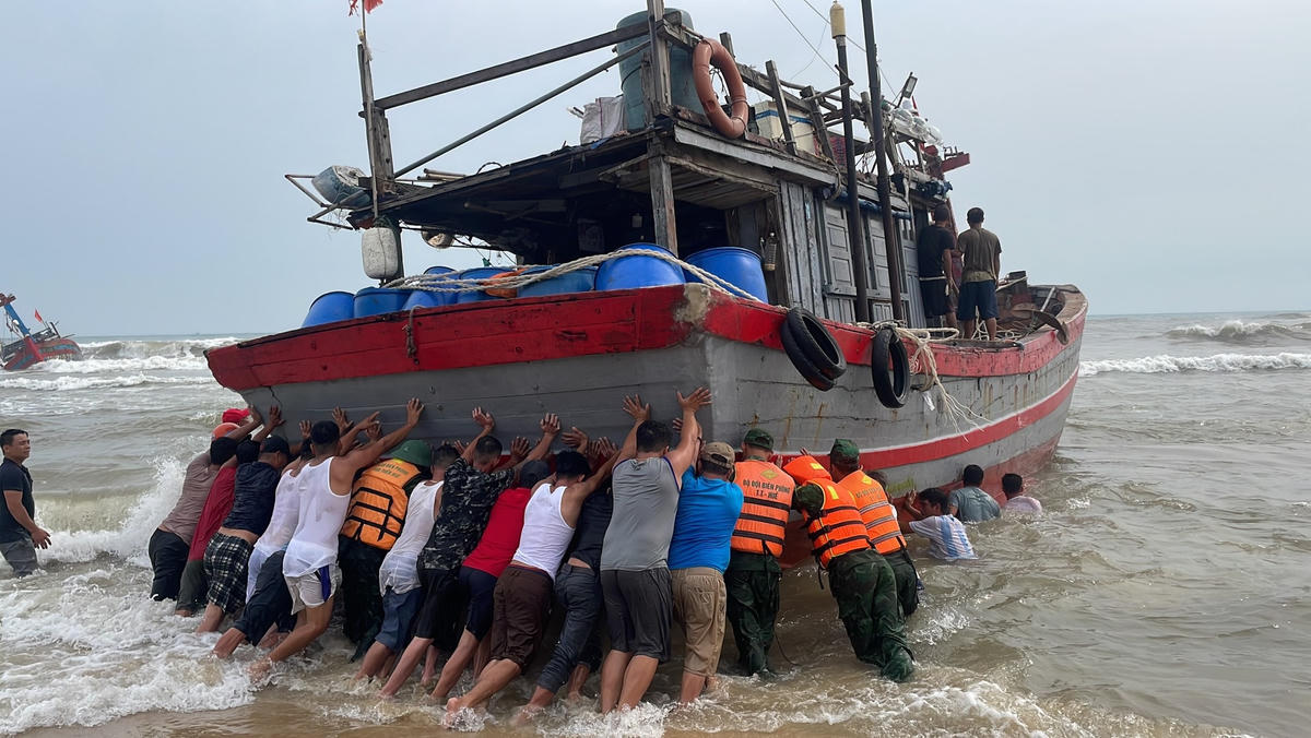 Lực lượng chức năng cùng người dân tiến hành cứu hộ, cứu nạn tàu cá gặp nạn. Ảnh: Ngọc Bình.