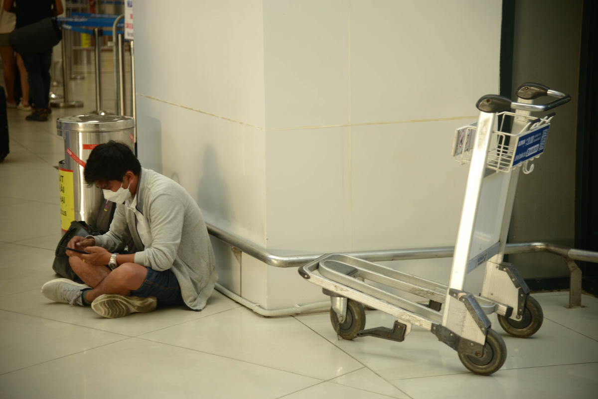Một số người ngồi bệt xuống đất để chờ đến lúc lên máy bay vì đã hết ghế để ngồi.