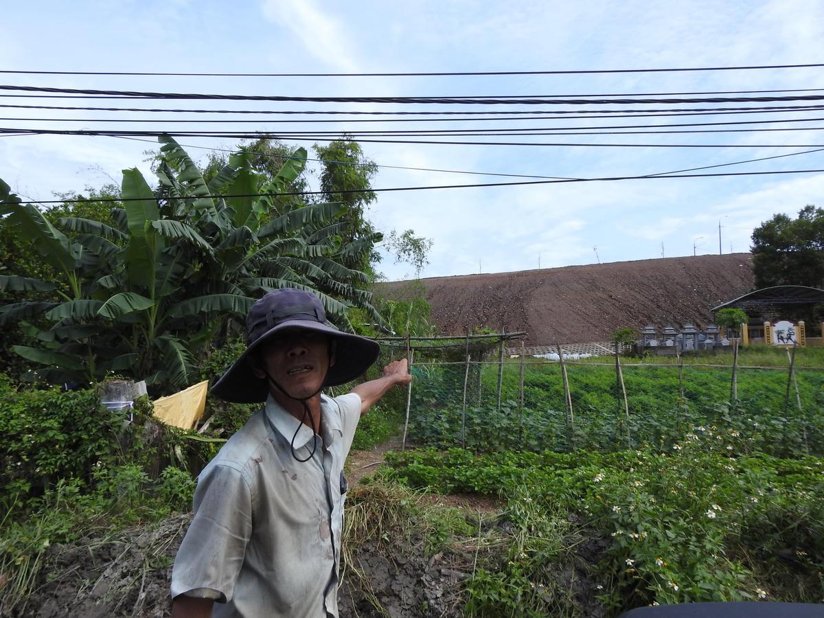 Ông Ngô Văn Tiên ở tổ 6 phường Hòa Thọ Tây và khu đất canh tác bị bùn tràn xuống. Ảnh: Thanh Tùng.