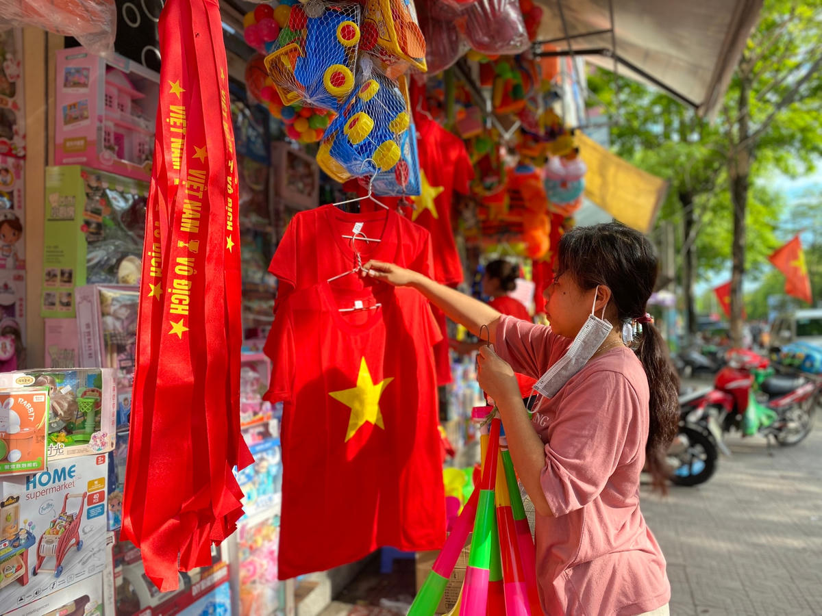 Các cửa hàng dọc tuyến phố gần SVĐ Cẩm Phả bày bán áo đỏ sao vàng cùng băng rôn cổ vũ...