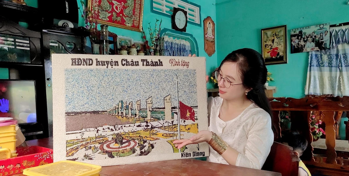 Chị Nguyễn Thị Tuyết Phượng bên bức tranh gạo phong cảnh quê hương Kiên Giang.  