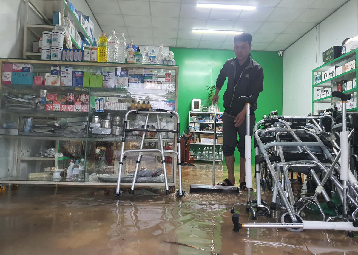 Anh Phạm Hưng đang lau dọn cửa hàng sau khi nước rút xuống.