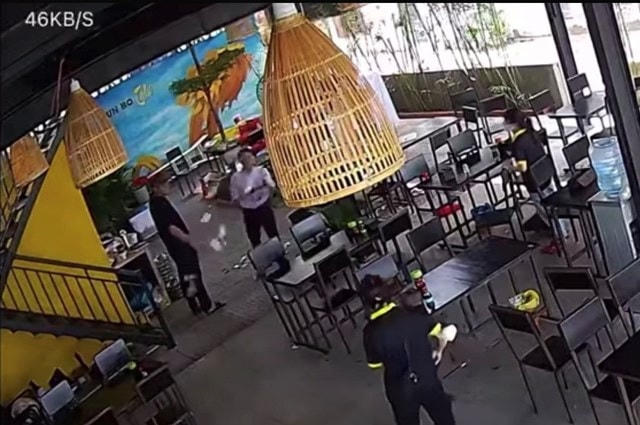 Ông Đặng Công Phước (áo trắng) ném tiền lẻ trong quán bún. Ảnh cắt từ clip.
