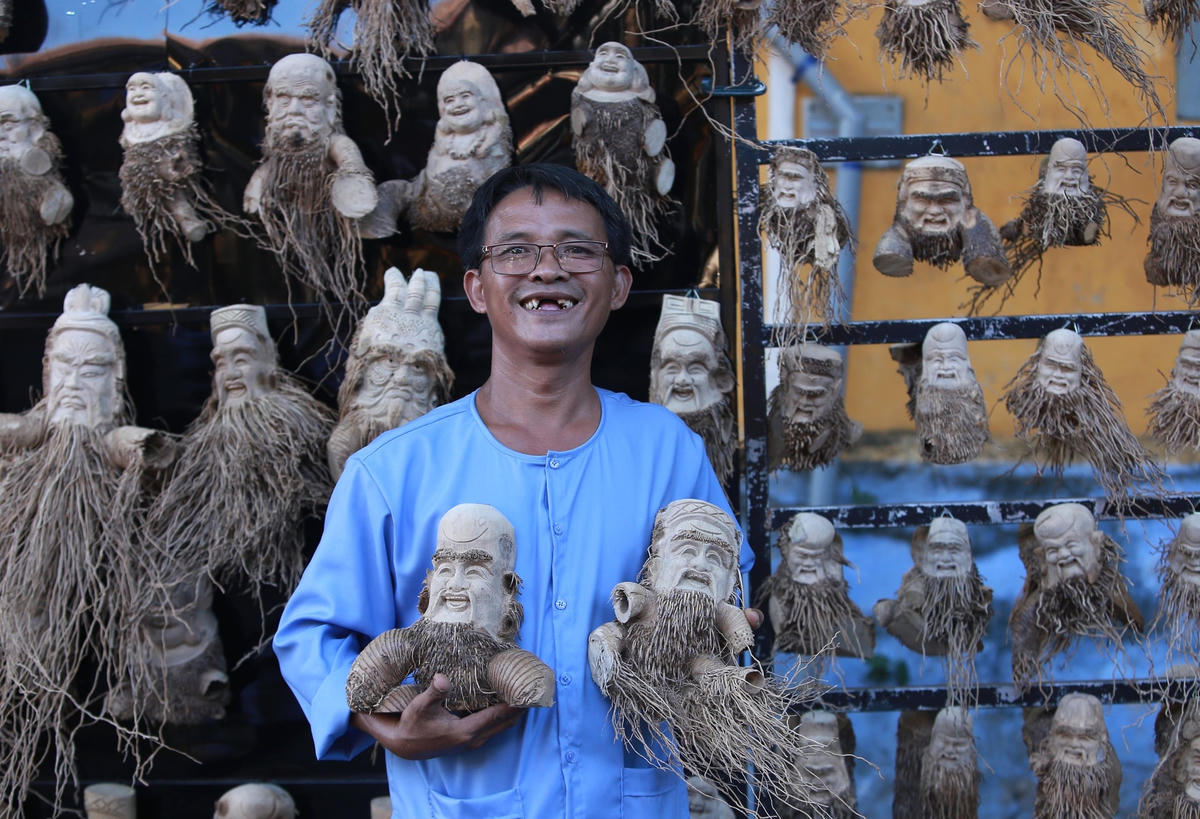 Anh Huỳnh Phương Đỏ bên sản phẩm điêu khắc từ gốc tre của mình.