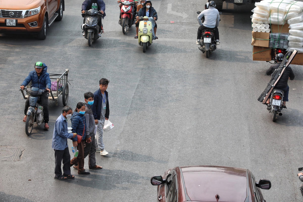 Từng nhóm người băng qua đường mặc cho dòng phương tiện đang lao vun vút.