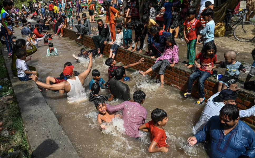 Người dân tắm mát ở một con kênh. Ảnh: Arif Ali / AFP / Getty Images.