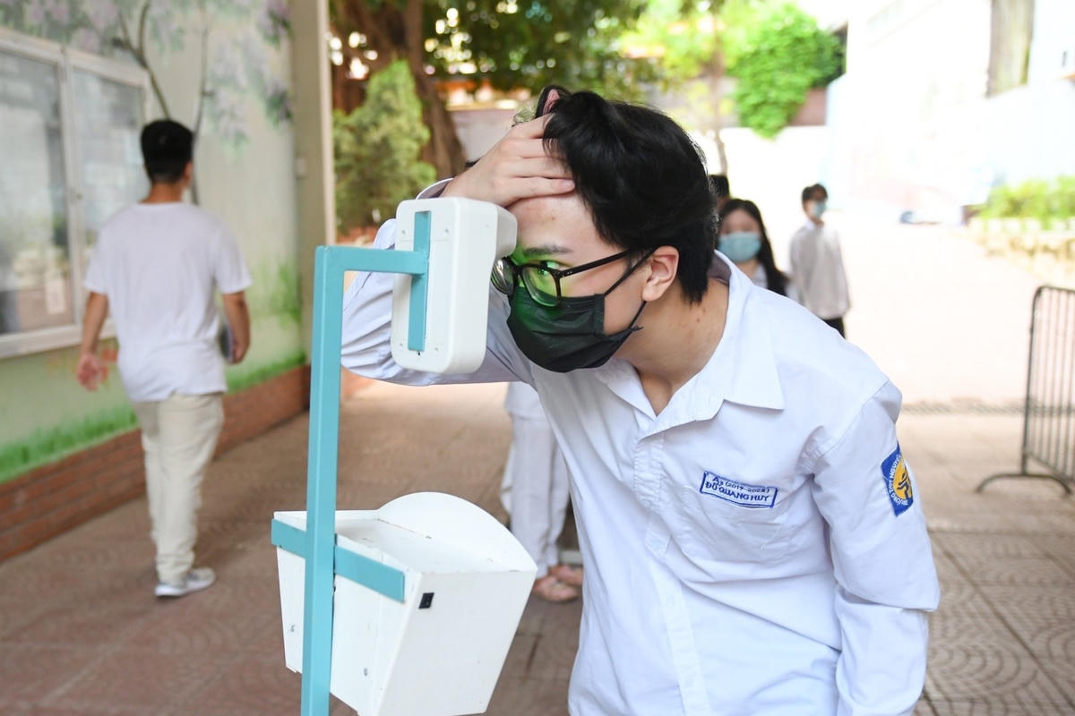 Thí sinh được hướng dẫn tự đo thân nhiệt trước khi vào trường thi.