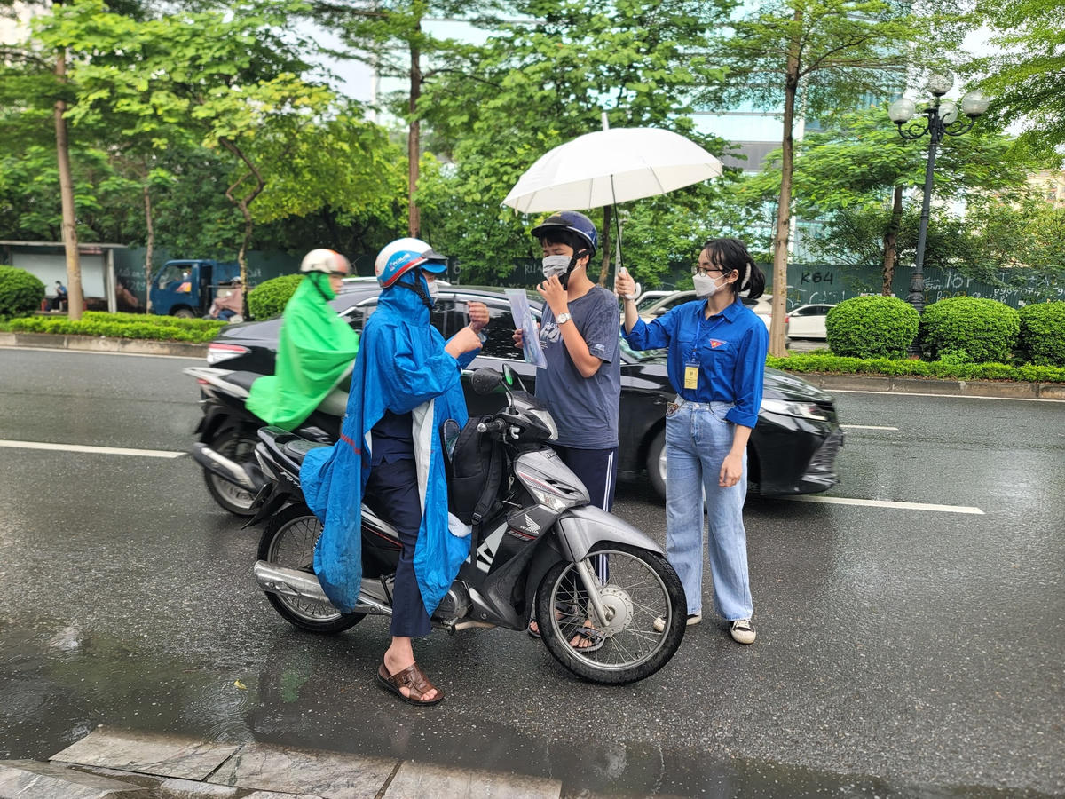 Sinh viên tình nguyện che mưa cho thí sinh từ xa.