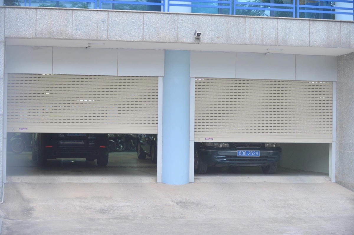 Hai xe biển xanh đỗ bên trong trụ sở Cục Đăng kiểm Việt Nam, cửa được kéo xuống.