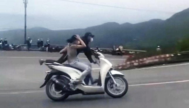Cặp vợ chồng "diễn xiếc", điều khiển xe máy đi lùi ở đoạn dốc cao phía Nam đỉnh đèo Hải Vân. Ảnh cắt từ clip.