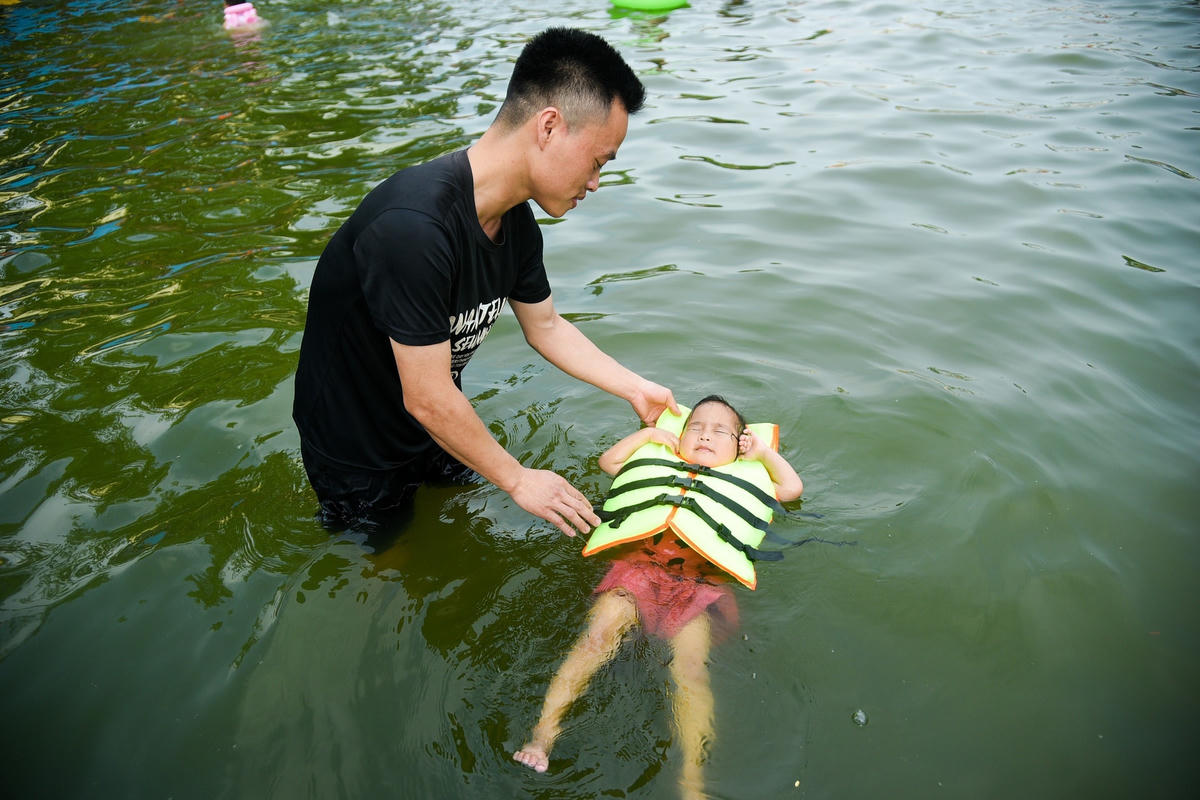 Các em nhỏ được phụ huynh dạy bơi.