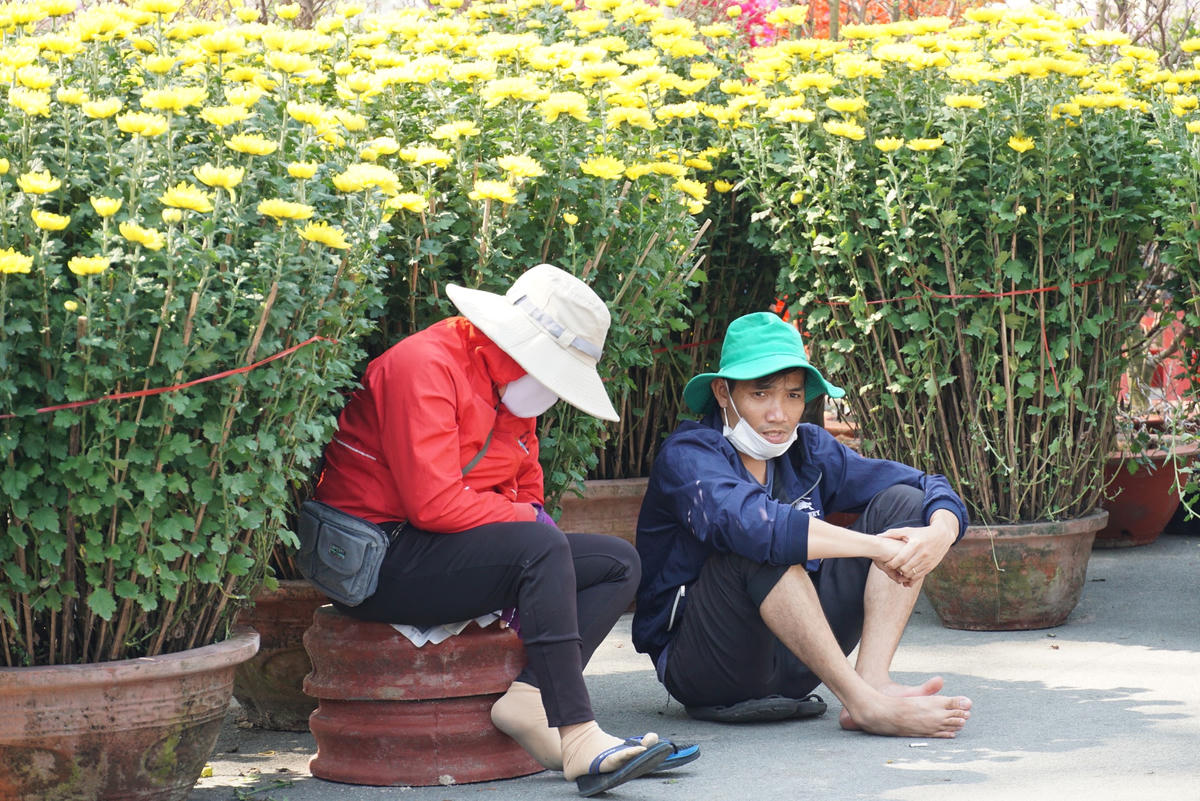 Người bán mệt mỏi ngồi chờ khách mua hoa.