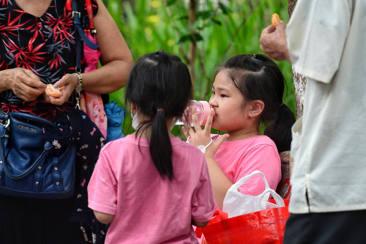 Các em nhỏ uống nước để giải khát sau thời gian đi dạo tại công viên.