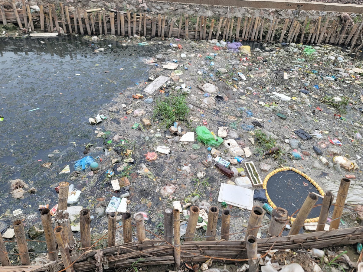 Rác phủ kín mặt sông, nước sông đen kịt, ô nhiễm, bốc mùi hôi thối.