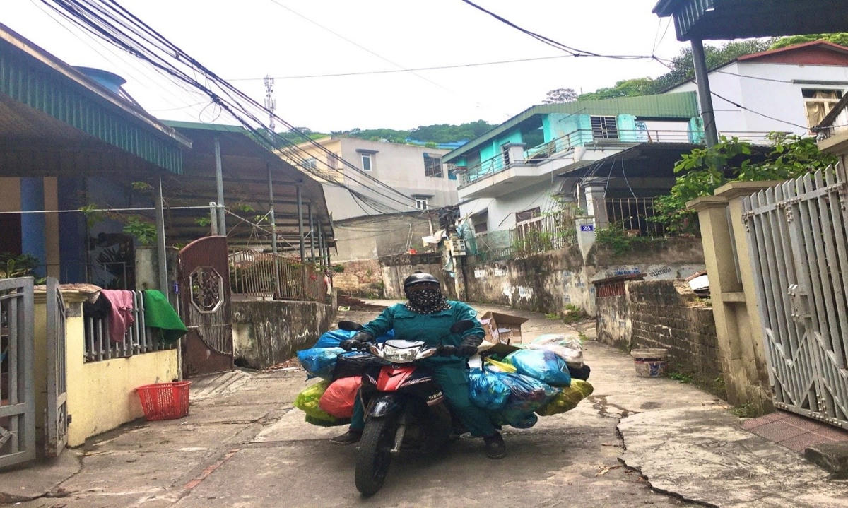 Nhân viên dọn vệ sinh môi trường dùng xe máy để đi thu gom rác trong khu dân cư.Chiếc xe chở đầy ắp các loại rác thải được đựng sẵn trong túi nilon.
