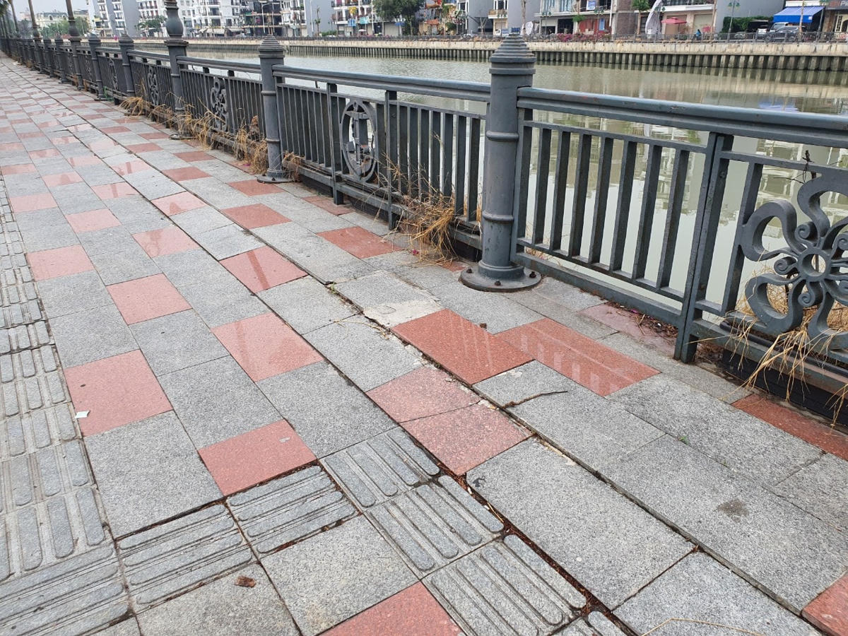 Đá lát tường bao bờ sông với đá vỉa hè vỉa hè bị vênh, hở.
