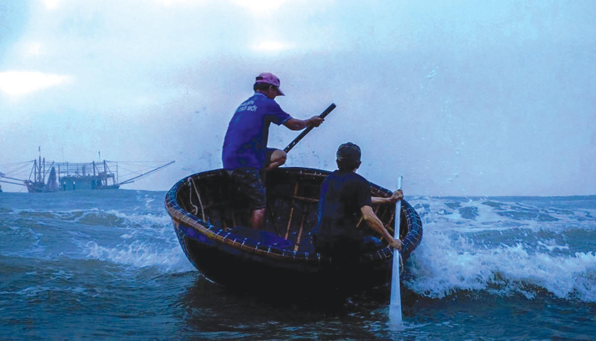 Thuyền thúng chở hải sản vượt sóng từ mờ sáng về chợ cá.  