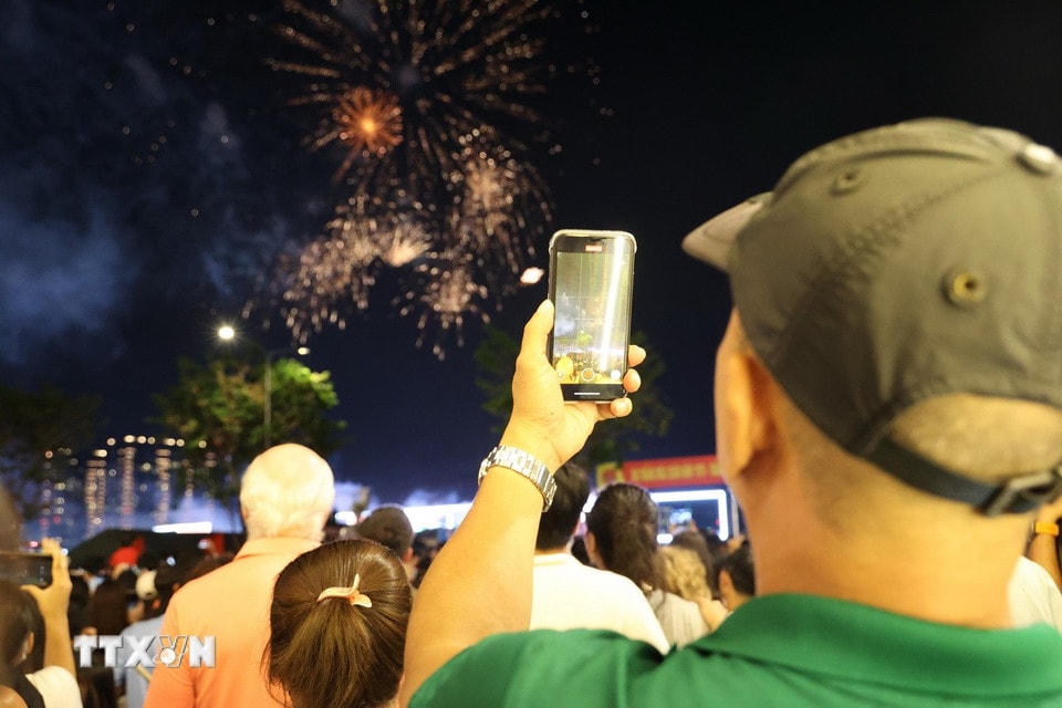 Người dân ghi lại khoảnh khắc tuyệt đẹp của màn pháo hoa ở Thành phố mang tên Bác. (Ảnh: Thu Hương/TTXVN)