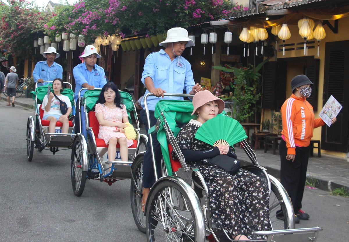 Du khách ngồi xích lô ngắm nhìn phố cổ Hội An.  