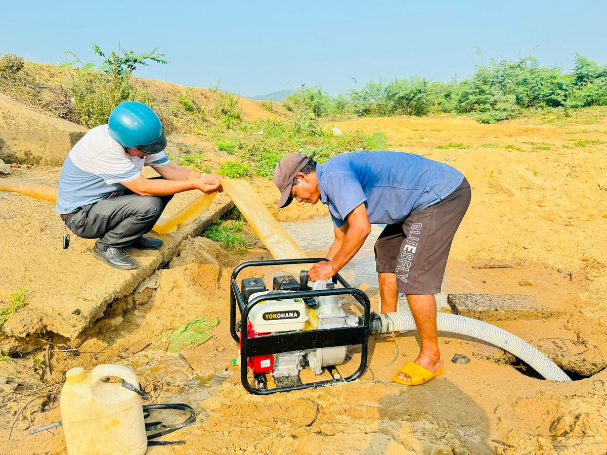 Ông Y KaPôk đang nối ống bơm nước ra ruộng.